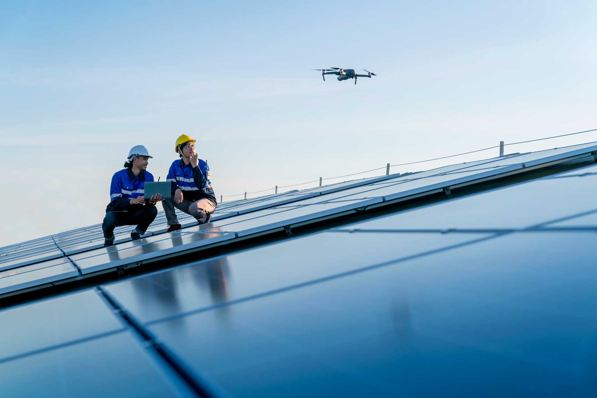 Two drone pilots surveying a roof with a drone